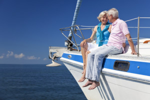 A happy senior couple sitting on the deck of a sail boat on a calm blue sea